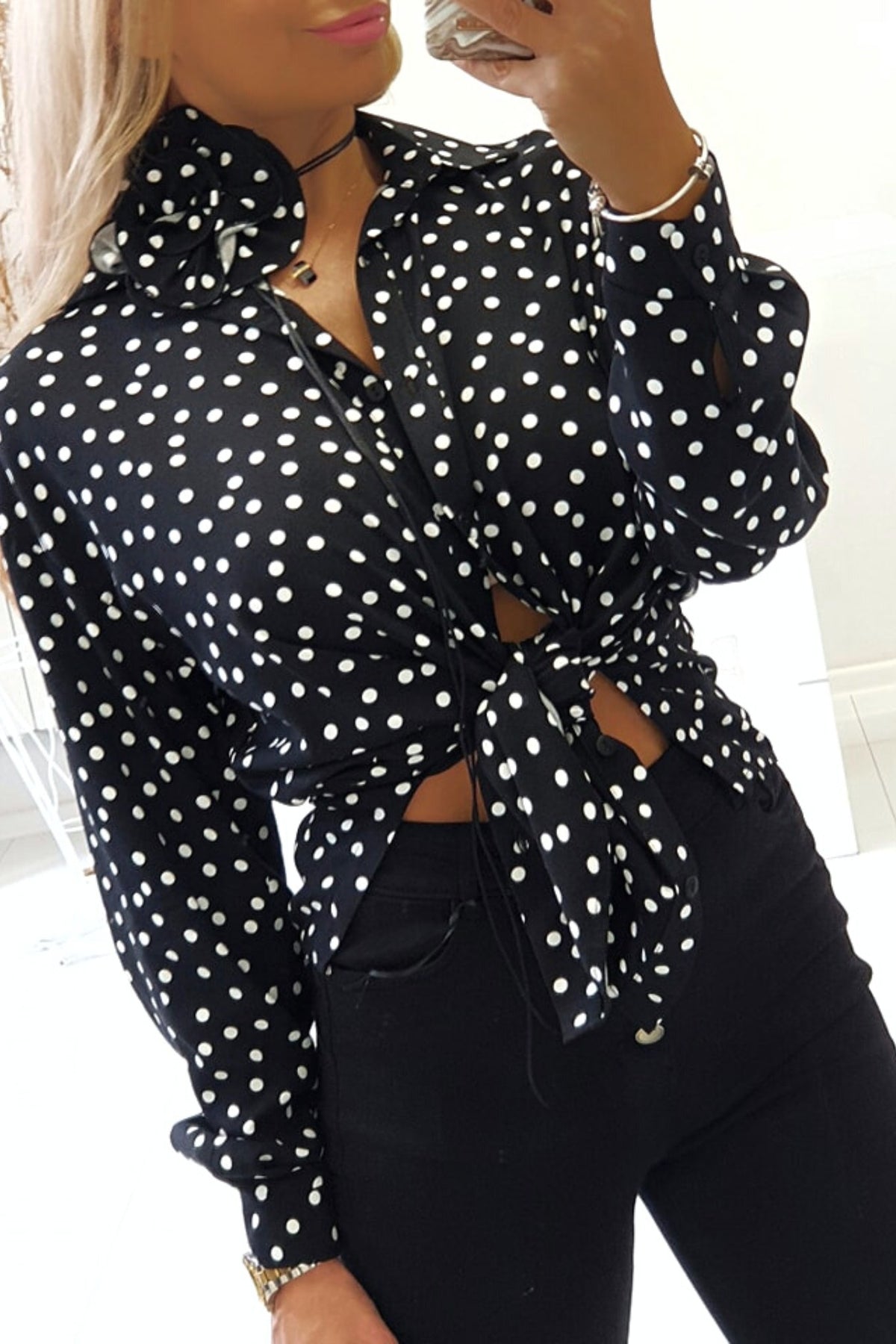 Camicia nera a pois bianchi in viscosa di Moda-Mania, con fiore in tessuto come dettaglio decorativo.