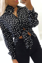 Camicia nera a pois bianchi in viscosa di Moda-Mania, con fiore in tessuto come dettaglio decorativo.