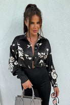 Camicia nera Moda-Mania con fantasia floreale beige, tessuto satinato, taglio comodo e bottoni dorati.