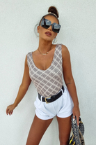 Canotta Moda-Mania con scollo a V, tessuto elasticizzato fantasia su sfondo beige, vestibilità comoda e stile alla moda.