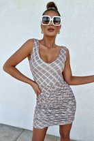 Canotta Moda-Mania con scollo a V in tessuto elasticizzato fantasia su sfondo beige, abbigliamento femminile estivo.