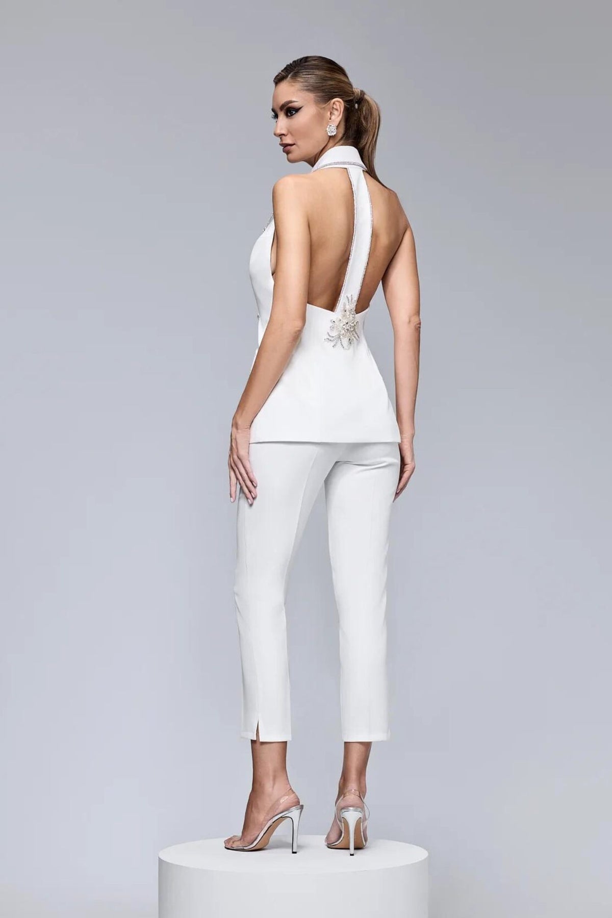 Completo elegante bianco Bby con gilet con schiena scoperta, dettagli con strass e pantaloni a sigaretta.