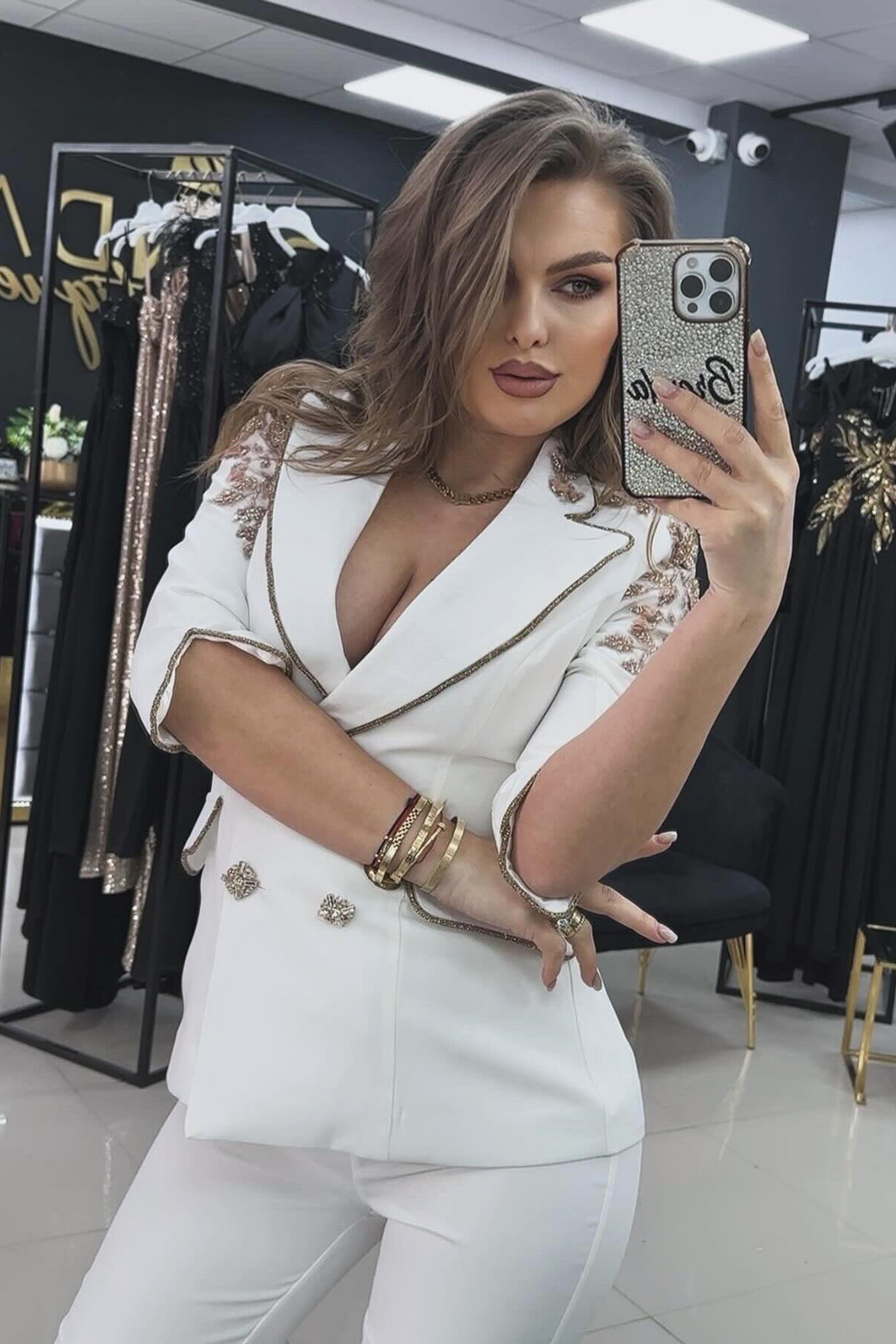 Completo tailleur bianco Bby con giacca con rifiniture e inserti in paillettes rosa dorate e pantaloni a sigaretta.