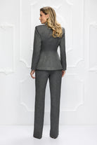 Completo tailleur elegante Bby con giacca grigia gessata, bottoni dorati e pantaloni a gamba larga, stile sofisticato e moderno.