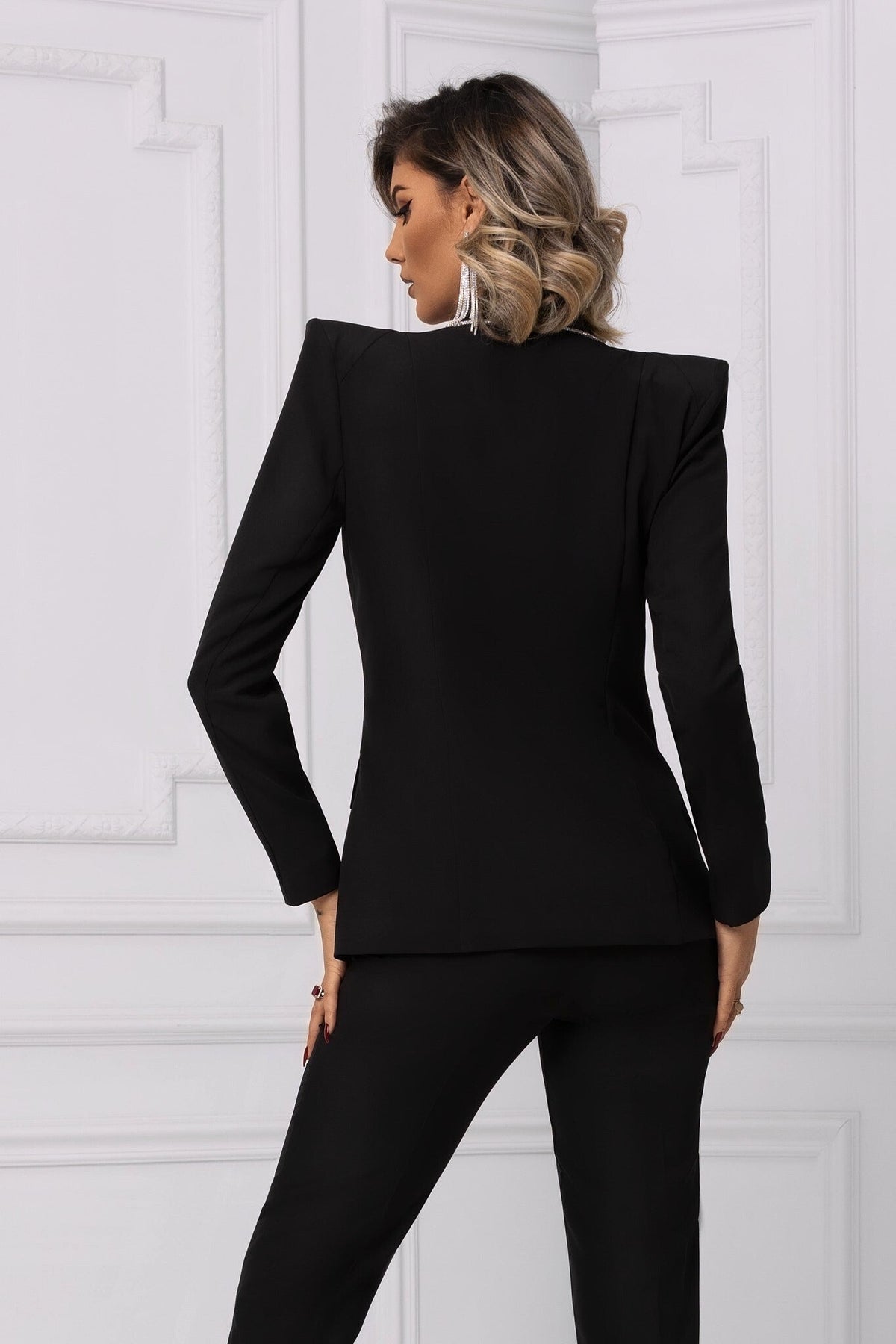 Completo tailleur nero Bby con giacca e pantaloni, rifiniture in strass argento e spalle larghe accessoriate.