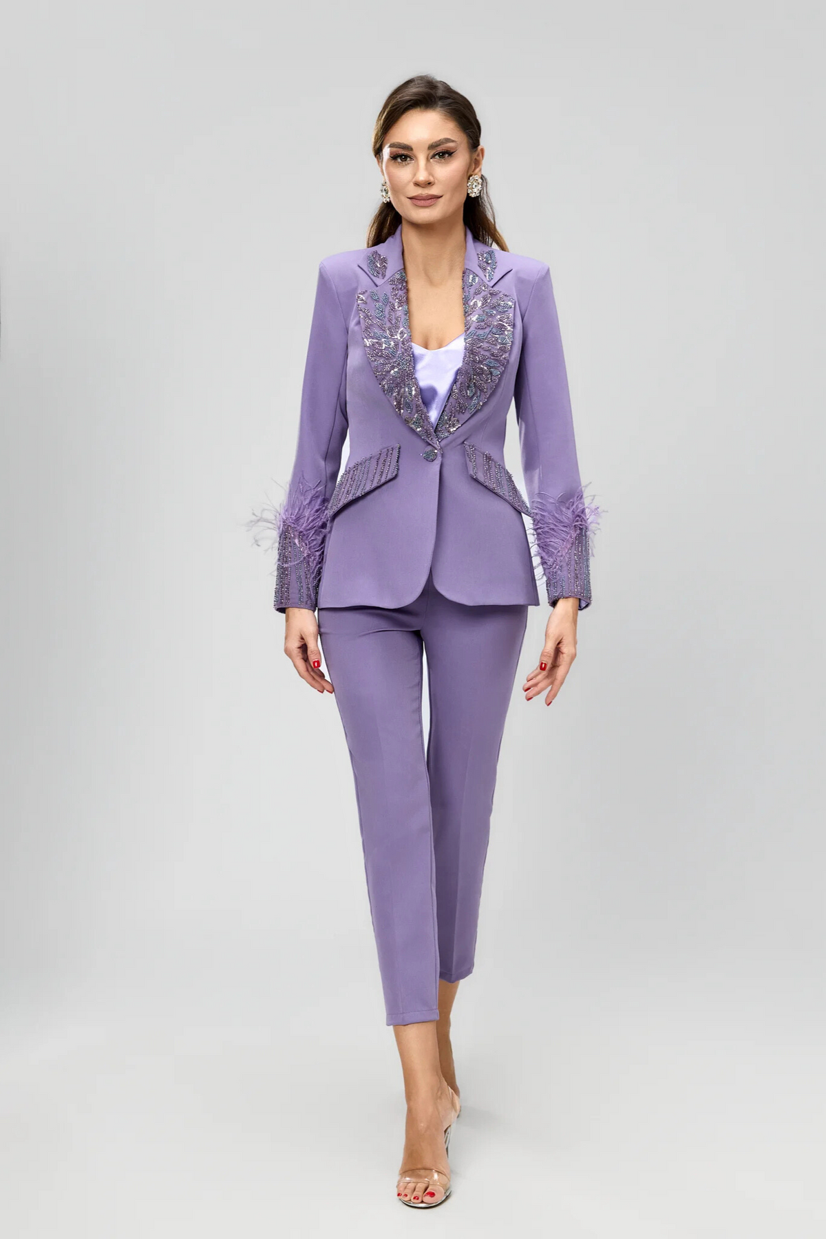 Completo tailleur Bby con giacca lilla impreziosita da piume e ricami in perline, pantaloni a sigaretta eleganti e raffinati.