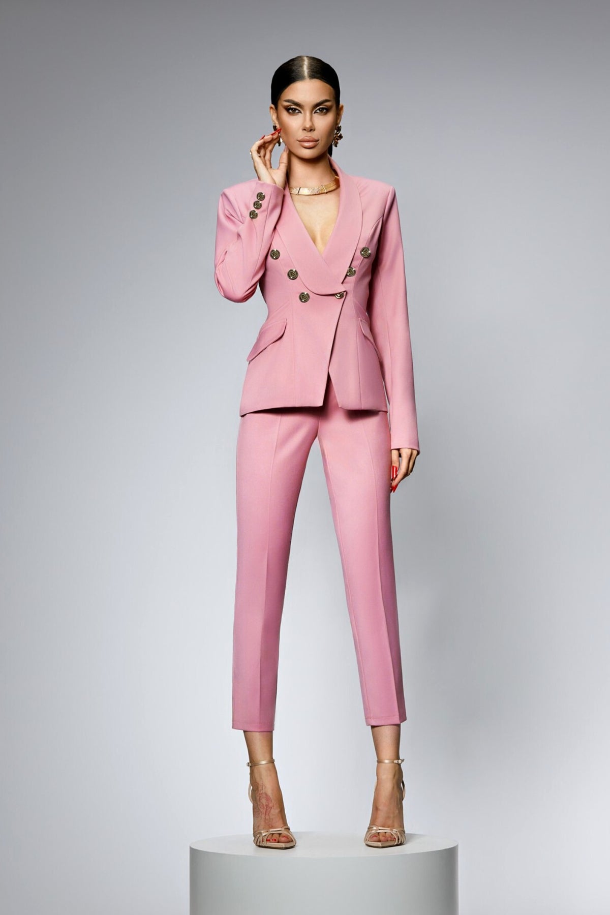 Completo tailleur rosa Bby con giacca doppiopetto e pantalone, accessoriato con bottoni metallici dorati, stile elegante e femminile.