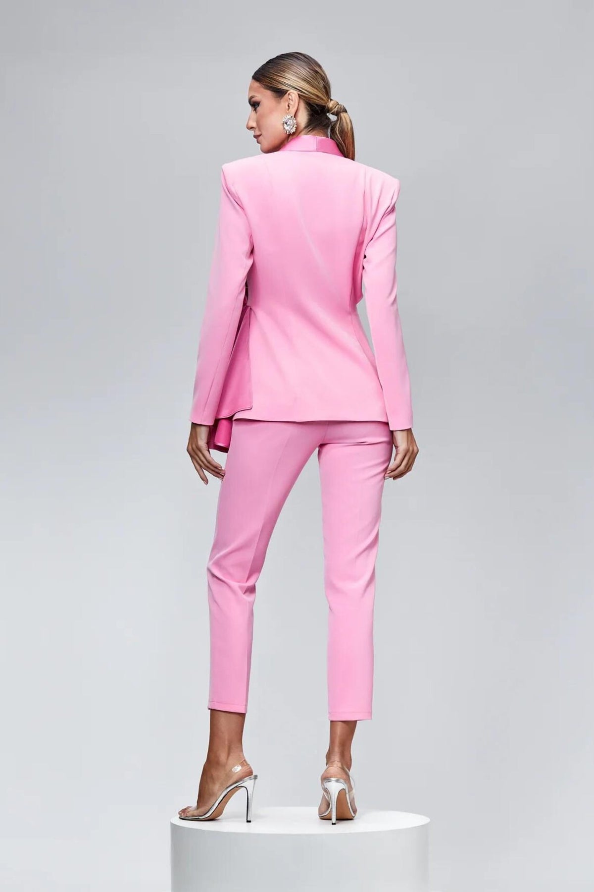 Completo tailleur rosa Bby con bottoni gioiello, volant, fiocco e dettaglio cut-out in vita, giacca e pantalone elegante e femminile.