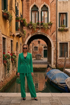 Completo tailleur verde Moda-Mania con giacca doppiopetto, cintura allacciabile e pantaloni larghi, stile elegante e moderno.