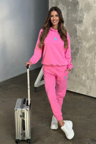 Completo tuta sportivo Moda-Mania in cotone fucsia con laccetti e logo fucsia, vestibilità comoda e stile casual.