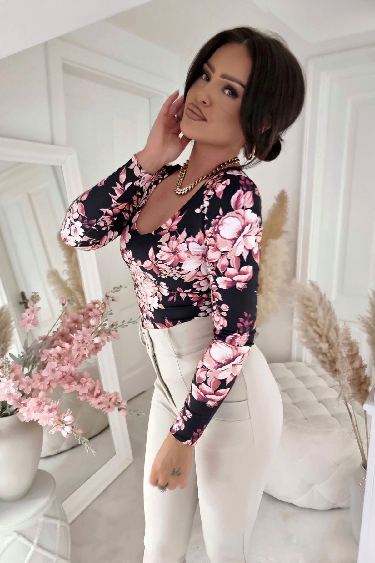 Maglia nera con stampa floreale rosa, scollo a V reversibile, moda-manìa, dettaglio di maglieria femminile elegante.
