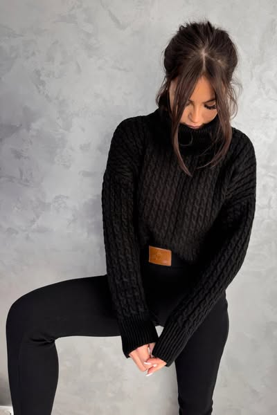 Maglione oversize nero in filato morbido con trecce, collo alto e polsini a coste, di Moda-Mania, stile cocoon.