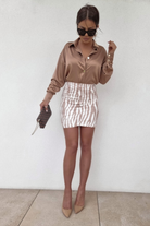 Minigonna corta a vita alta aderente fantasia zebrata bianco beige con arricciature, moda moderna e di tendenza.
