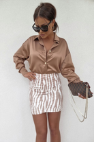 Minigonna corta a vita alta aderente fantasia zebrata bianco-beige con arricciature, moda moderna e femminile.