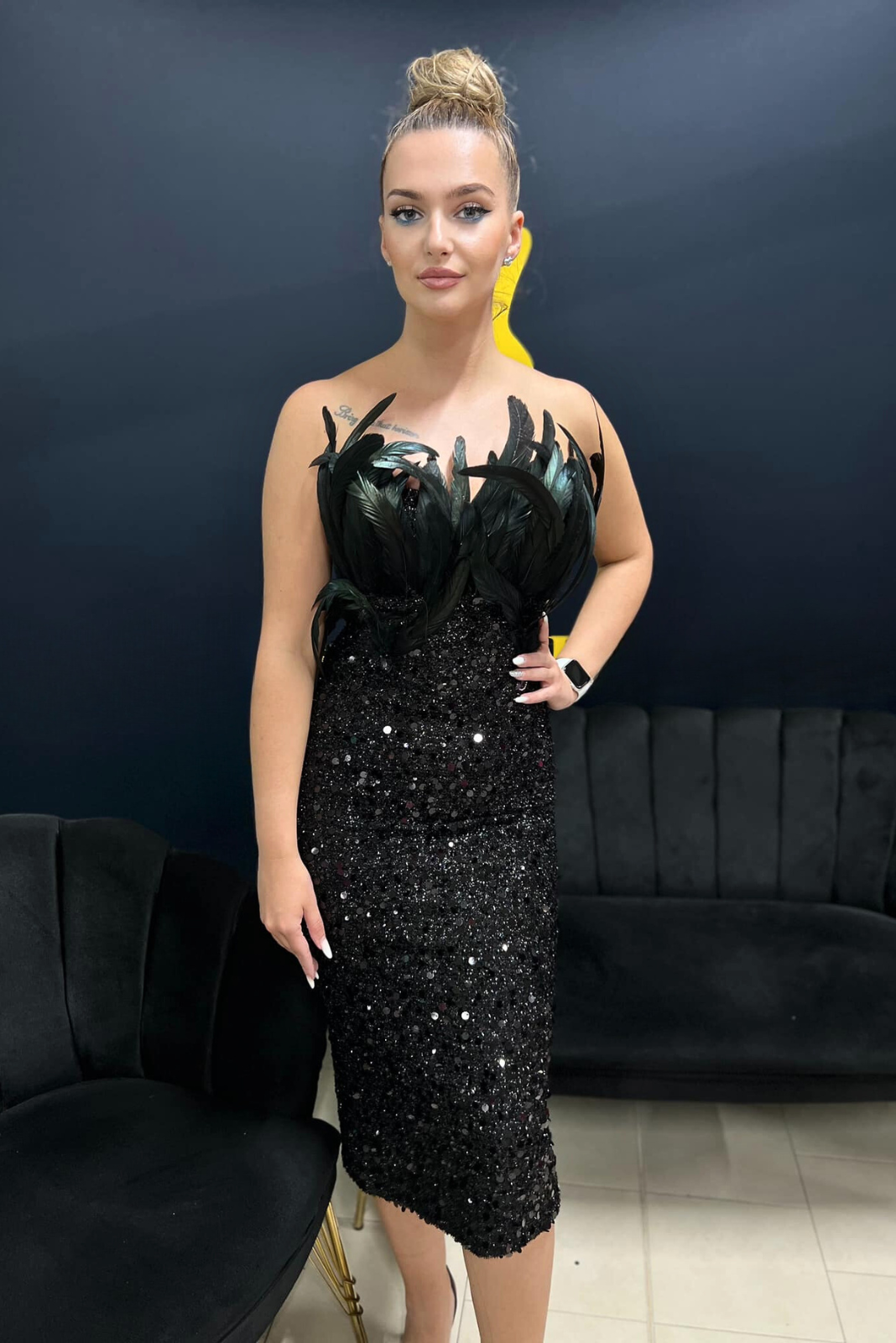 Abito nero aderente midi con paillettes, scollo a cuore e dettagli di piume decorativi, di Moda-Mania.