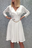 Abito bianco svasato con manica lunga e cintura, abiti corti moda-mania, dettaglio del vestito con accessoriata cintura.