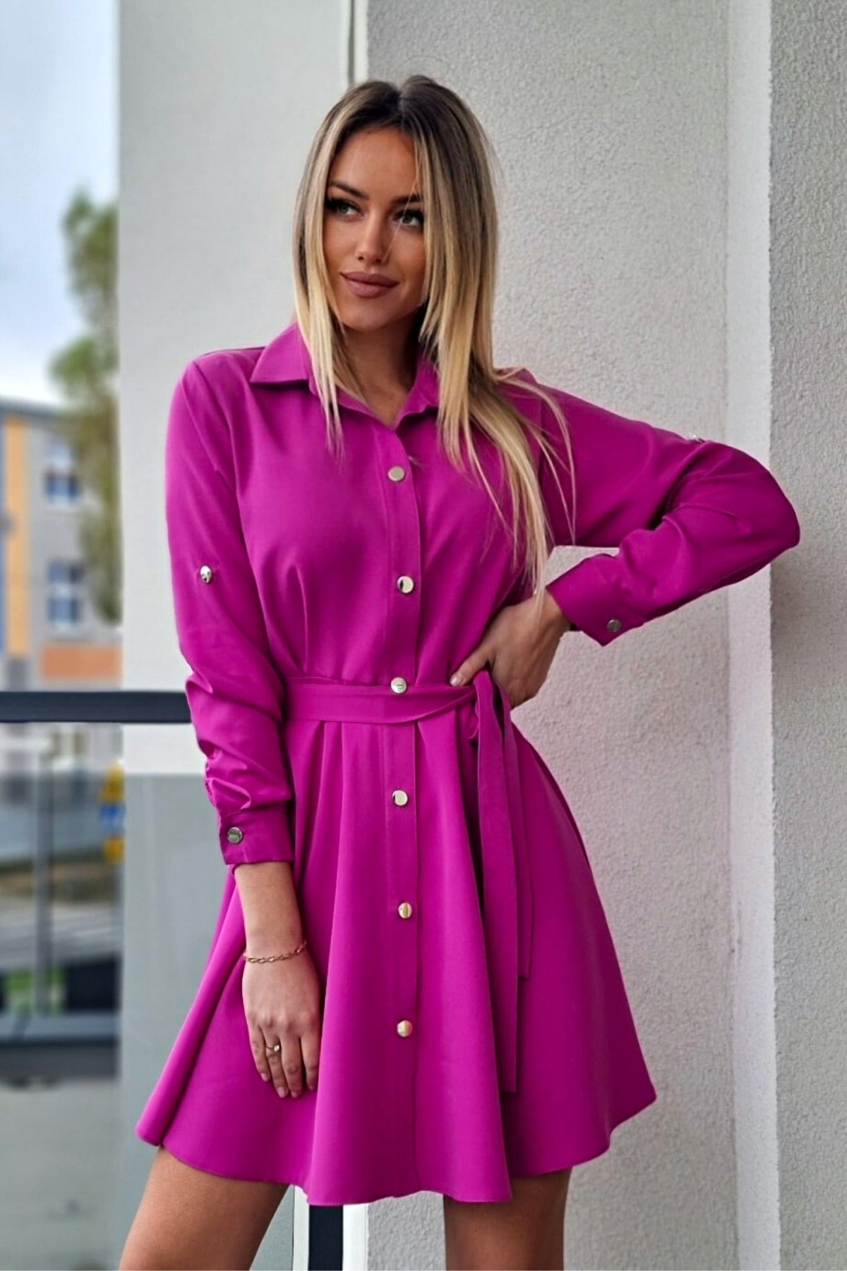 Abito camicia svasato colore magenta di Moda-Mania con bottoni dorati e cinturino, dettaglio di un abito corto femminile.