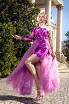 Abito corto fucsia a fiori con manica singola, gonna lunga e ampia in tulle, marca Moda-Mania, dettaglio visibile in foto.