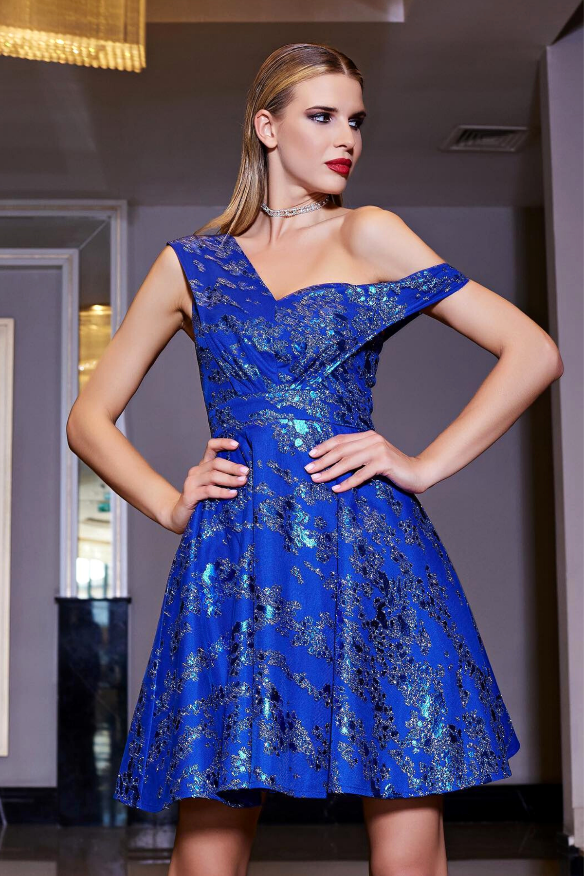 Abito corto svasato blu elettrico con fantasia glitterata e spalla cadente, firmato Moda-Mania.
