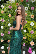 Abito lungo aderente verde smeraldo con paillettes, piume e strass, firma Moda-Mania, dettagli decorativi eleganti e raffinati.