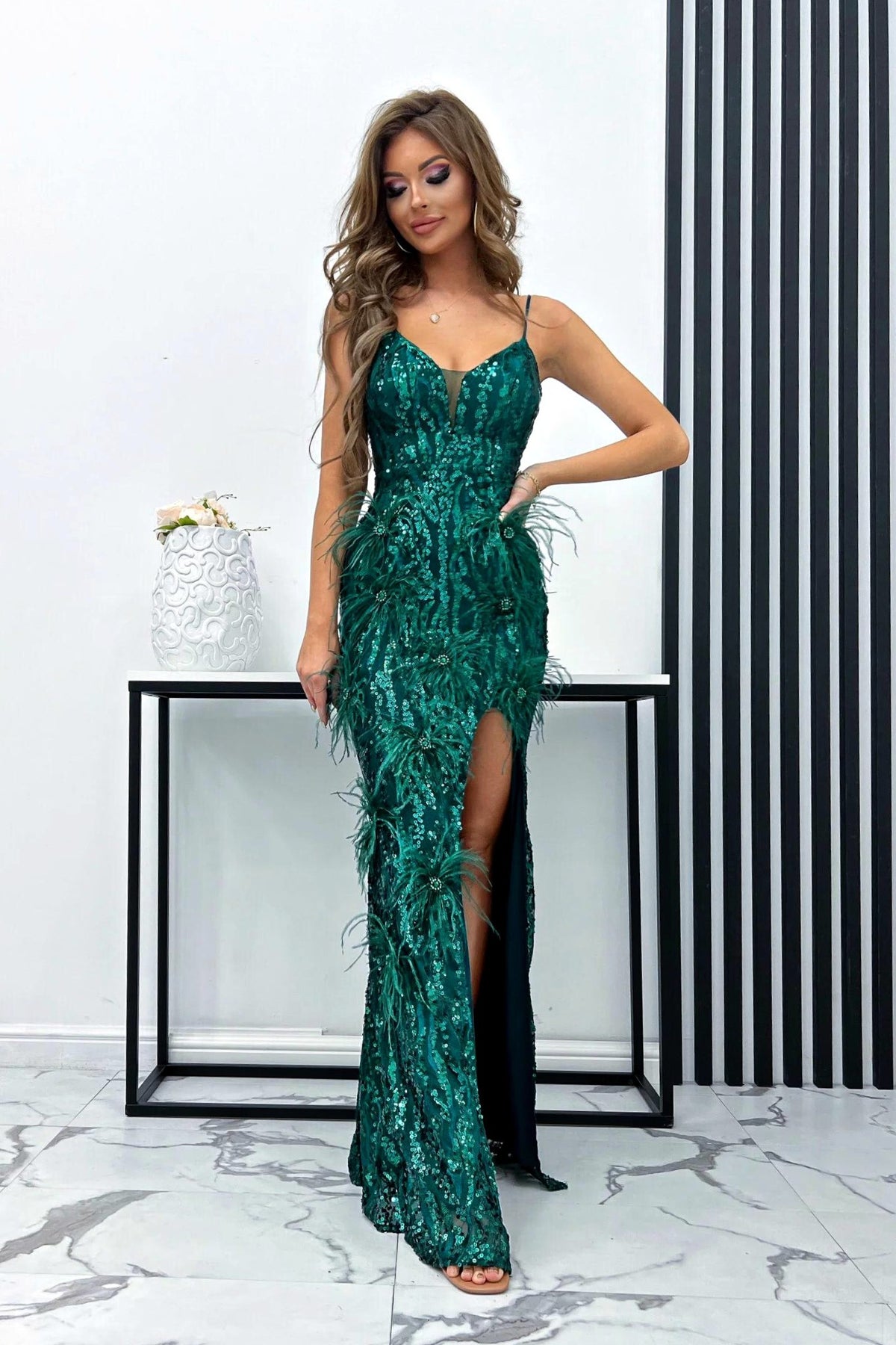 Abito lungo aderente verde smeraldo Moda-Mania con paillettes, piume e strass, decorazioni eleganti e dettagli raffinati.