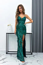 Abito lungo aderente verde smeraldo Moda-Mania con paillettes, piume e strass, decorazioni eleganti e dettagli raffinati.
