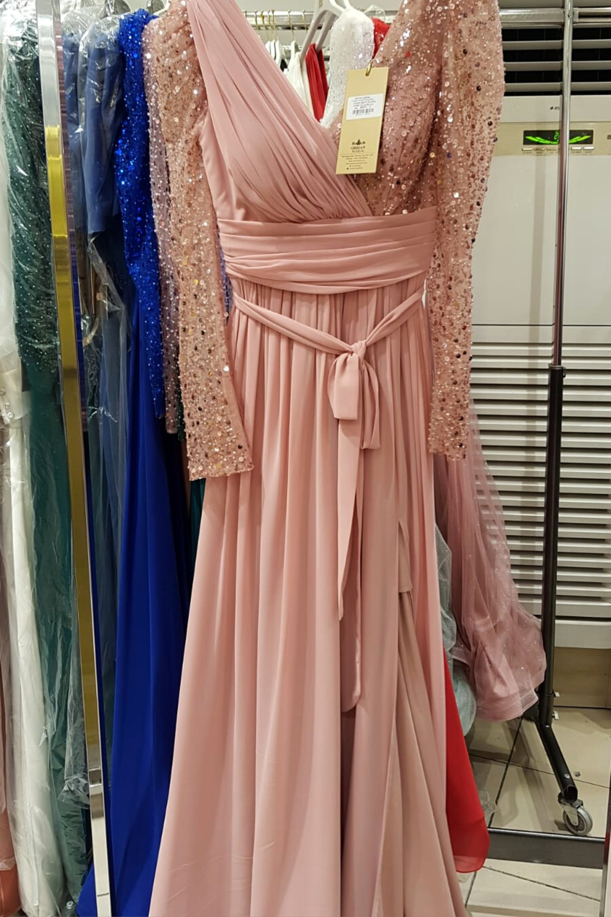 Abito lungo svasato rosa Moda-Mania con maniche lunghe, tulle, perline e paillettes, dettaglio elegante e femminile.
