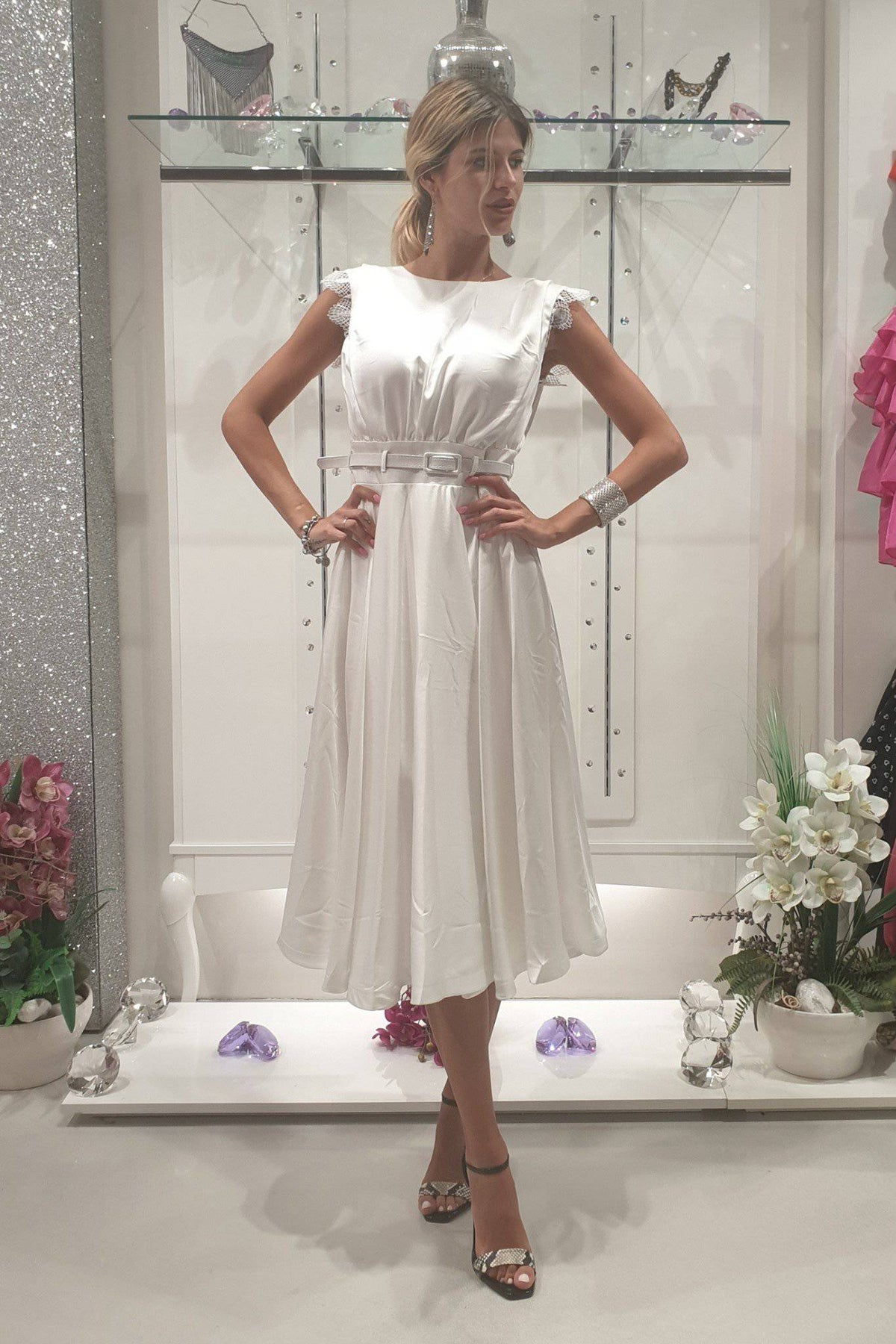 Abito svasato bianco Moda-Mania con gonna a ruota in tessuto satinato, dettagli in pizzo e cintura inclusa, vestibilità elegante.