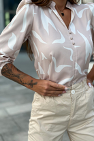 Blusa beige Moda-Mania con stampa astratta bianca, scollo a V e bottoncini, tessuto leggero e stile elegante.