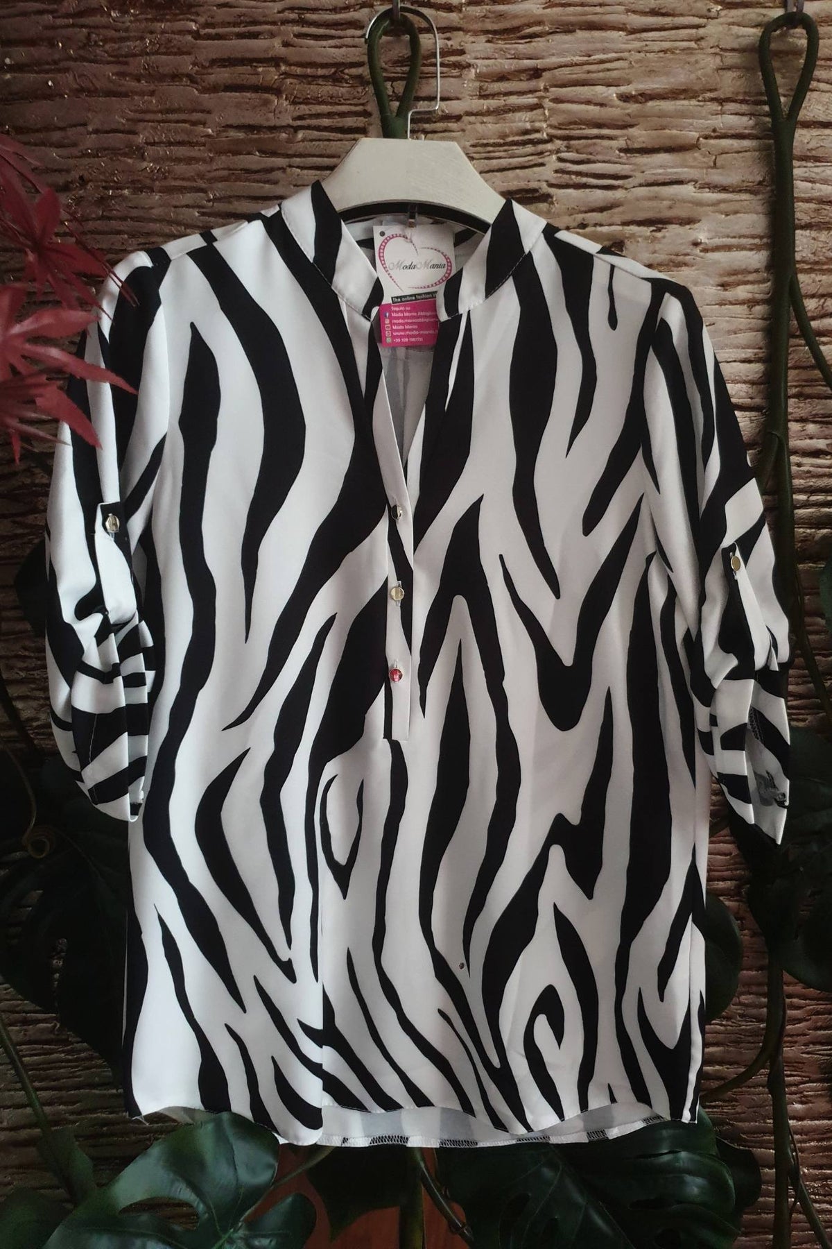 Blusa bianca zebrata Moda-Mania con maniche tre quarti e bottoni dorati, dettaglio di stile elegante e alla moda.
