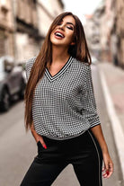 Blusa casual Moda-Mania a fantasia pied di poule bianca e nera, maniche tre quarti, scollo a V e bordi elasticizzati.