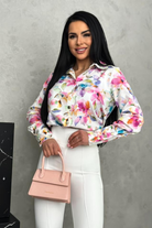 Camicia elegante bianca con fantasia floreale rosa, bottoni dorati, marca Moda-Mania, tessuto leggero e dettagli raffinati.
