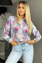 Camicia elegante bianca Moda-Mania con fantasia floreale rosa, bottoni dorati e dettagli raffinati, vestibilità femminile e stile sofisticato.