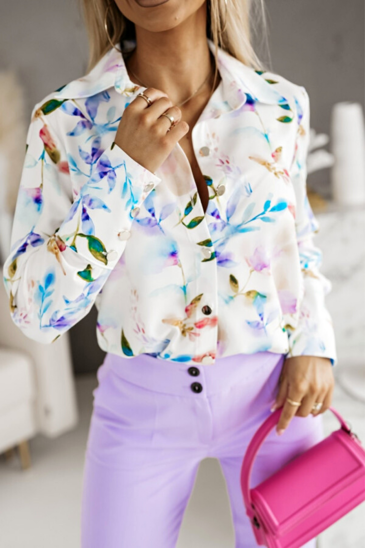Camicia elegante bianca Moda-Mania con fantasia foglie multicolori e bottoni dorati, tessuto leggero e dettagli raffinati.