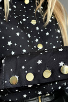 Camicia elegante nera Moda-Mania con fantasia pois e stelline bianche, bottoni dorati, tessuto raffinato e stile sofisticato.
