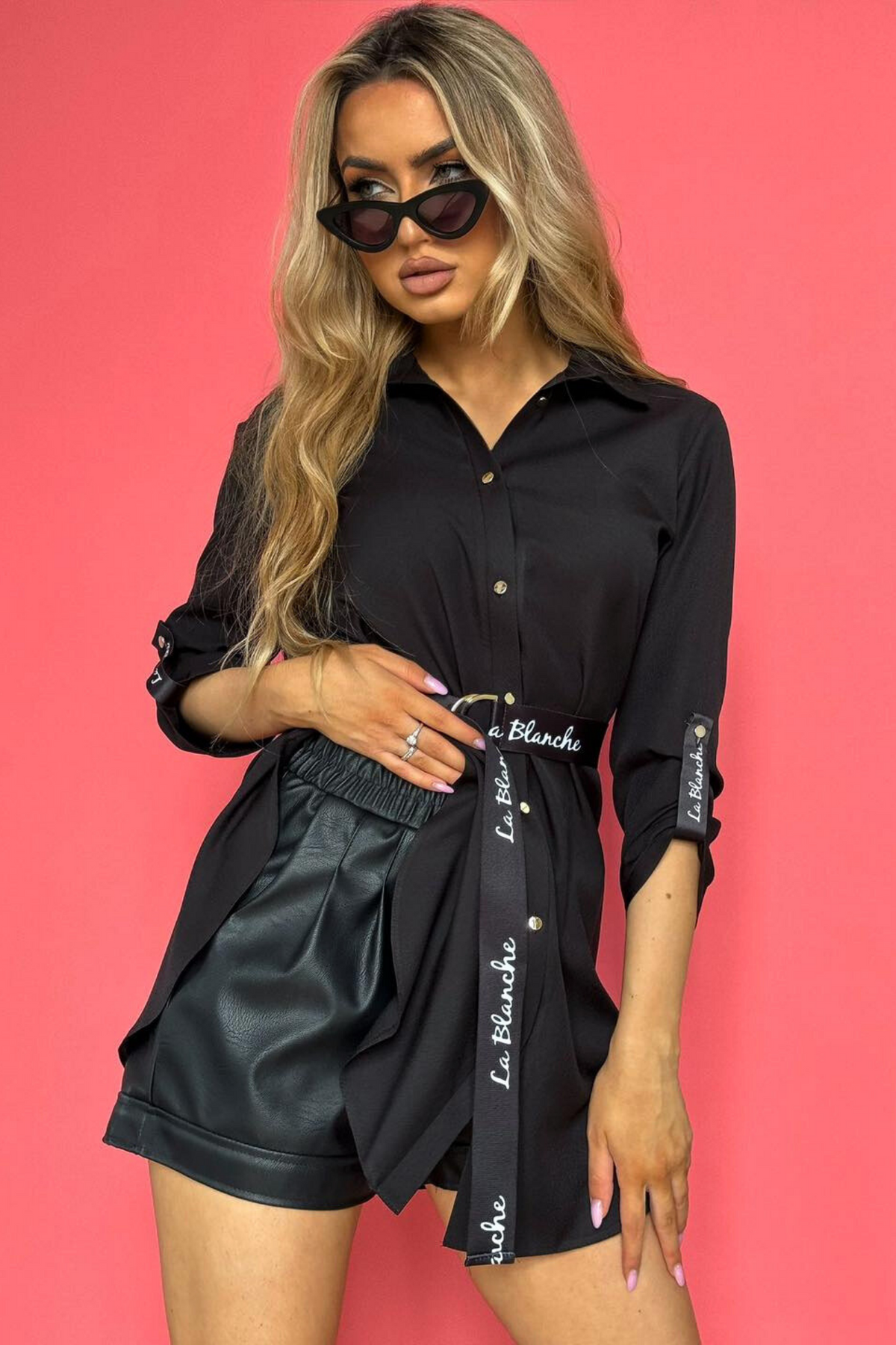 Camicia lunga nera Moda-Mania con taglio asimmetrico e cintura nera, tessuto morbido e dettagli eleganti, stile moderno.