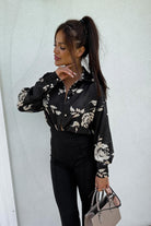 Camicia nera comoda con fantasia floreale beige, tessuto satinato e bottoni dorati, marca Moda-Mania, vista frontale.