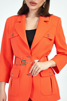 Completo tailleur arancione corallo Moda-Mania con giacca con tasche e pantaloni larghi, accessoriato con cintura.