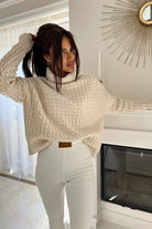 Maglione oversize Moda-Mania in filato morbido beige chiaro, collo alto e polsini a coste, con motivo a trecce, vista frontale.
