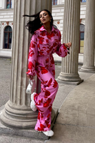 Pantaloni lunghi a palazzo rosa con fantasia di rose rosse, tasche laterali e vita medio alta, marchio Moda-Mania.