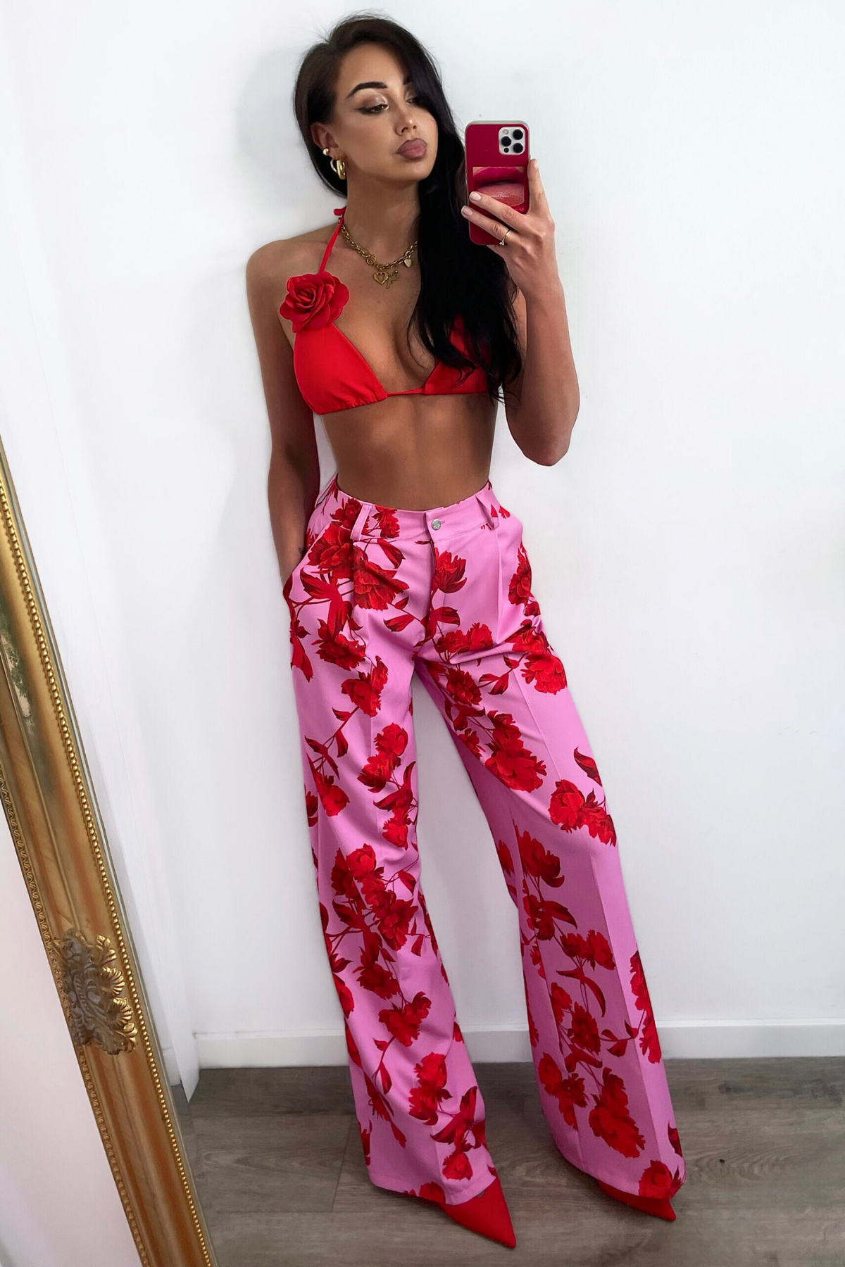 Pantaloni lunghi a palazzo rosa con fantasia di rose rosse, tasche laterali e vita medio alta, di marca Moda-Mania.