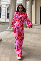 Pantaloni lunghi a palazzo rosa con fantasia di rose rosse, tasche laterali e vita medio alta, marca Moda-Mania.