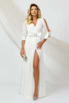 Abito lungo bianco Pretty Girl con spacco, maniche con aperture e fiocco con strass in vita, elegante e femminile.