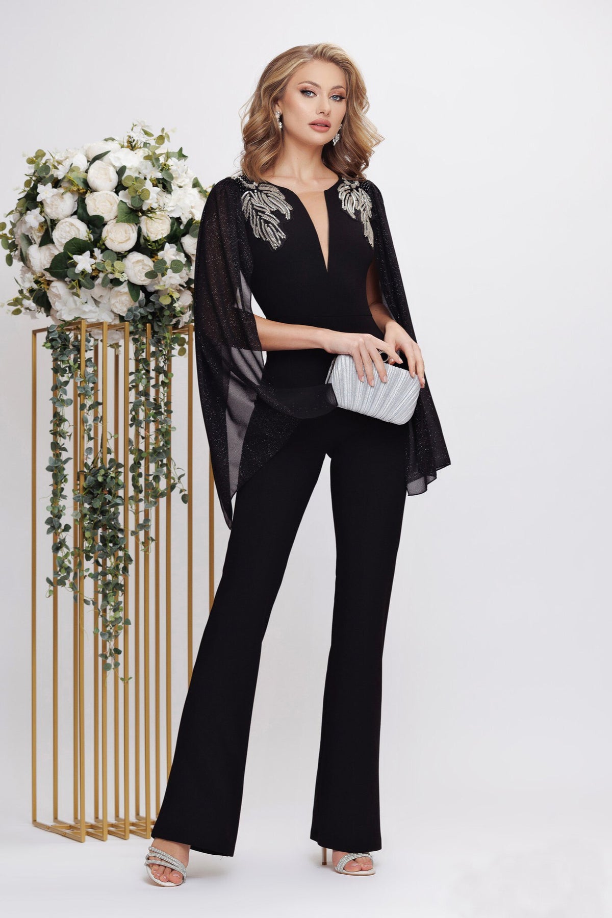 Salopette elegante nera Fofy, aderente ed elasticizzata con maniche aperte e dettagli argento sulle spalle.