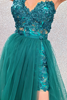 Abito lungo svasato verde smeraldo con gonna in tulle e corpetto a fiori 3D, moda-mania, elegante e femminile, dettaglio floreale.