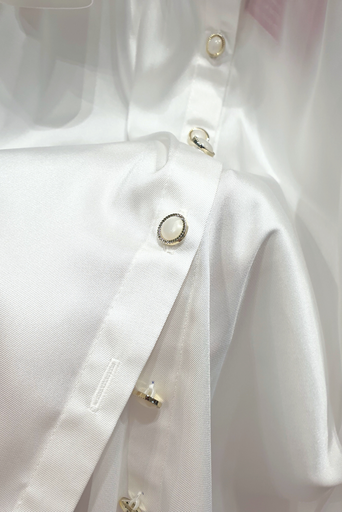 Camicia elegante bianca in tessuto satinato con maniche a sbuffo e bottoni gioiello bianchi