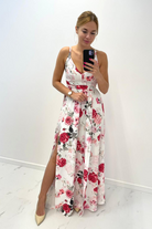 Abito lungo svasato estivo bianco con fantasia floreale rossa e rosa e spacchi laterali, marca Moda-Mania.