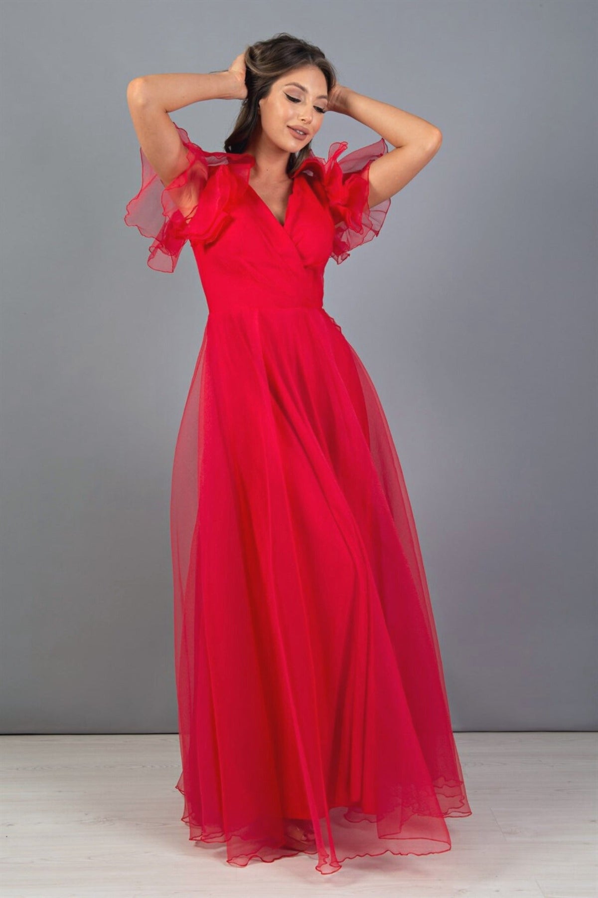 Abito lungo rosso svasato in organza di Moda-Mania con scollo a V e dettagli di volants sulle spalle.