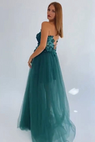 Abito lungo Moda-Mania con manica singola verde smeraldo, strascico in tulle e corpetto a fiori 3D.