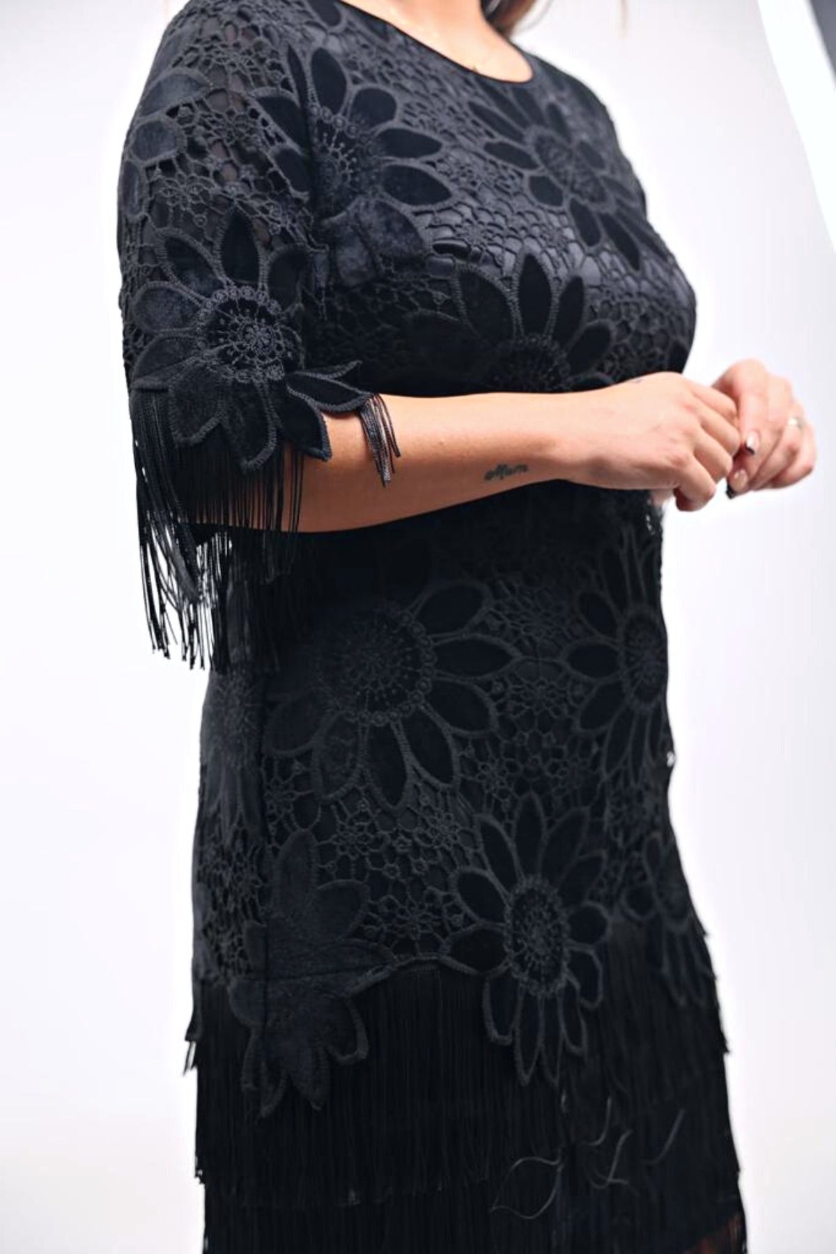 Abito nero corto linea dritta per donna curvy con ricami floreali e frange decorative, moda elegante e femminile.